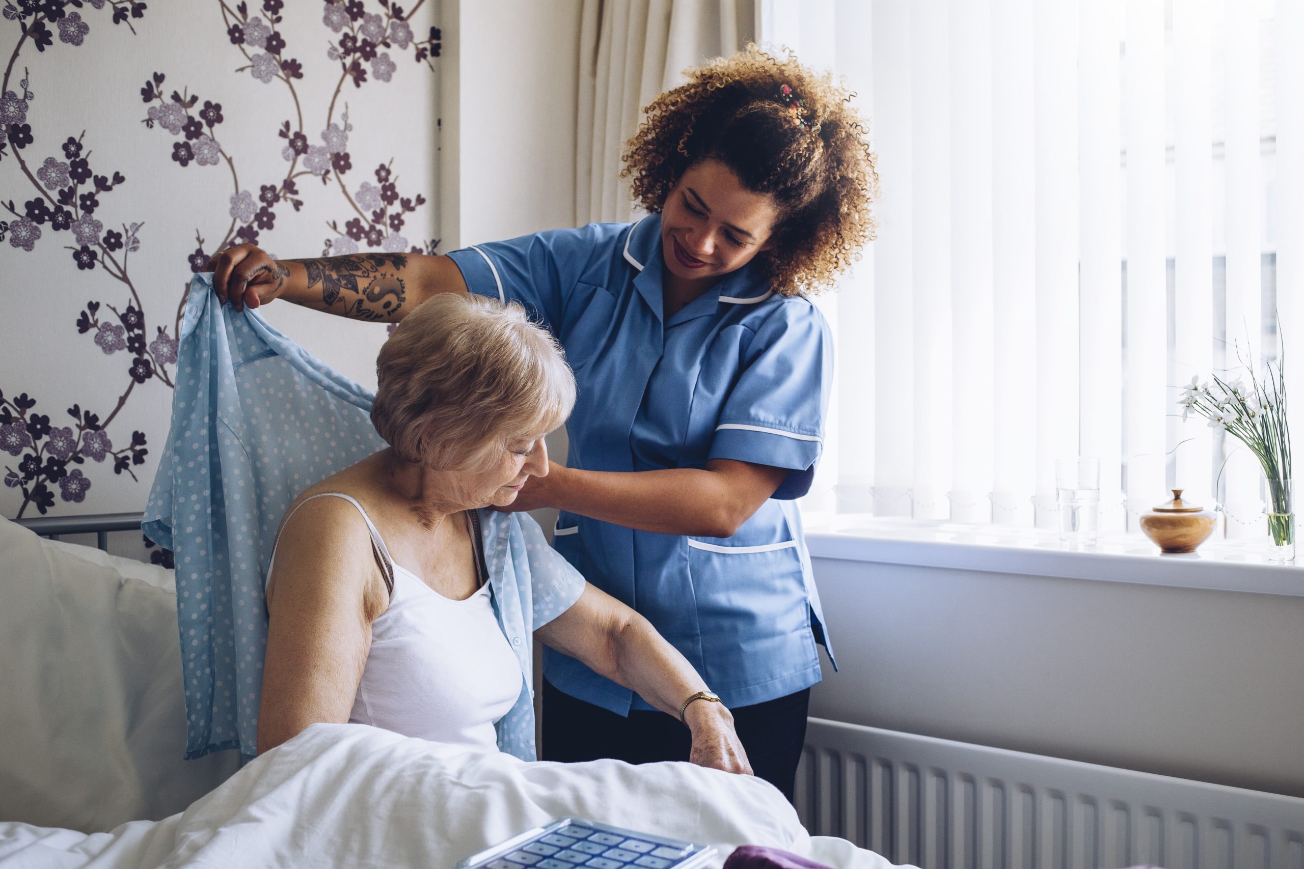 Photo of a nurse helping a hospice patient put on a shirt