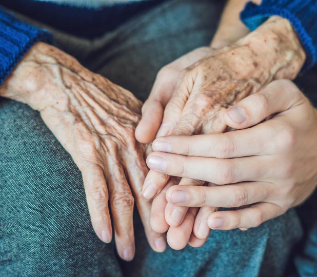 Photo of an elderly woman's hands being caressed by her granddaughter's hands