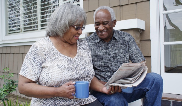 African American couple sitting on their porch with newspaper and coffee